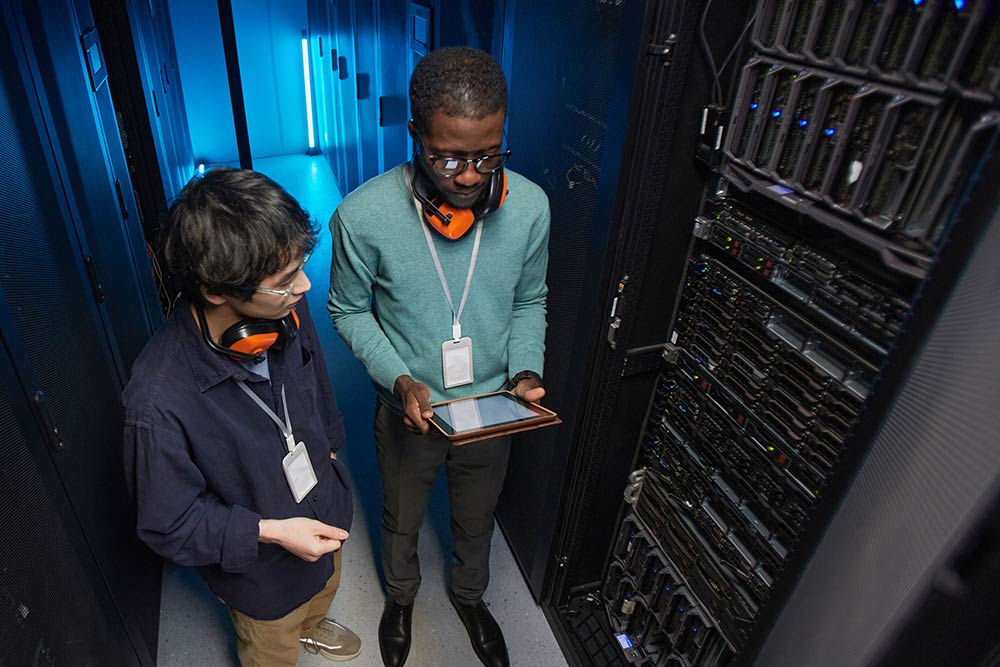 two tudents working on tablets in a server farm room