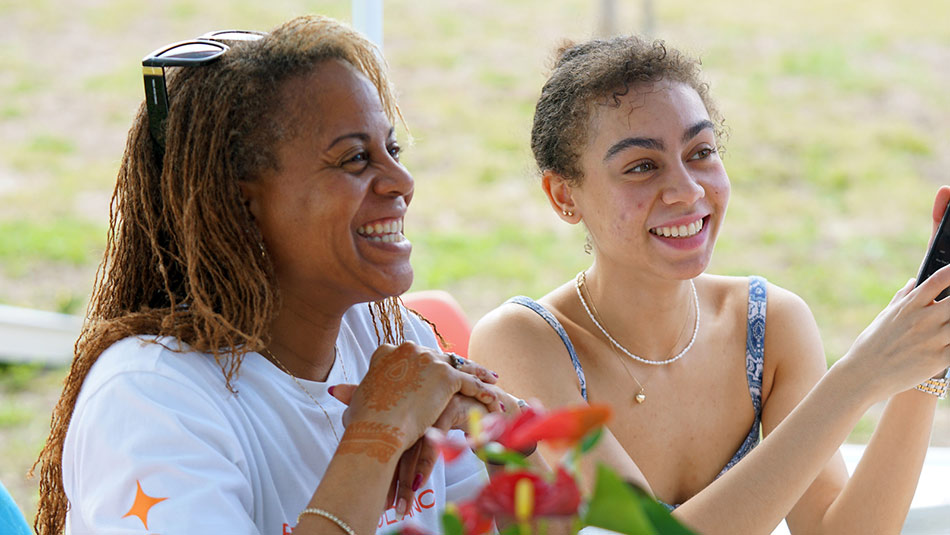 two female students talking and laughing with someone out of camera view