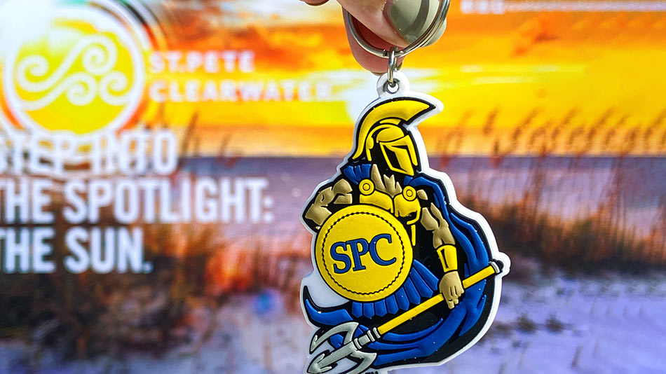 Keychain of Titus the blue and yellow Titan mascot dangling in front of a beach scene