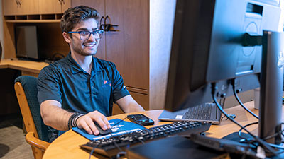 Velocity IQ employee and SPC graduate Theo Varitimidis sits at his computer