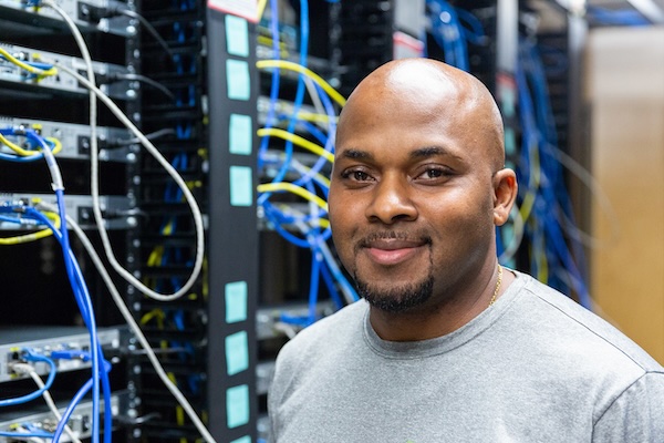 male student standing in front of a bank of servers