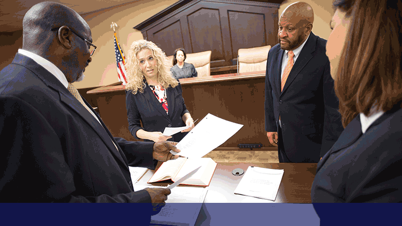 a group of male and female paralegals holding legal papers in a courtroom