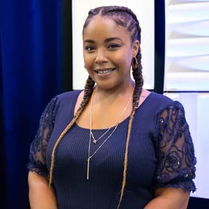 photo of Antoinette Catalano standing in front of a blue curtain smiling at the camera while wearing a blue shirt