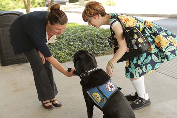 A female student, wearing a flowery dress, introduces her service dog to another woman on the SPC Seminole Campus.