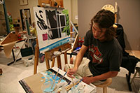 student wearing a headband creating a painting in a classroom