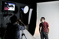 Photography shoot with a man in a red shirt against a white backdrop